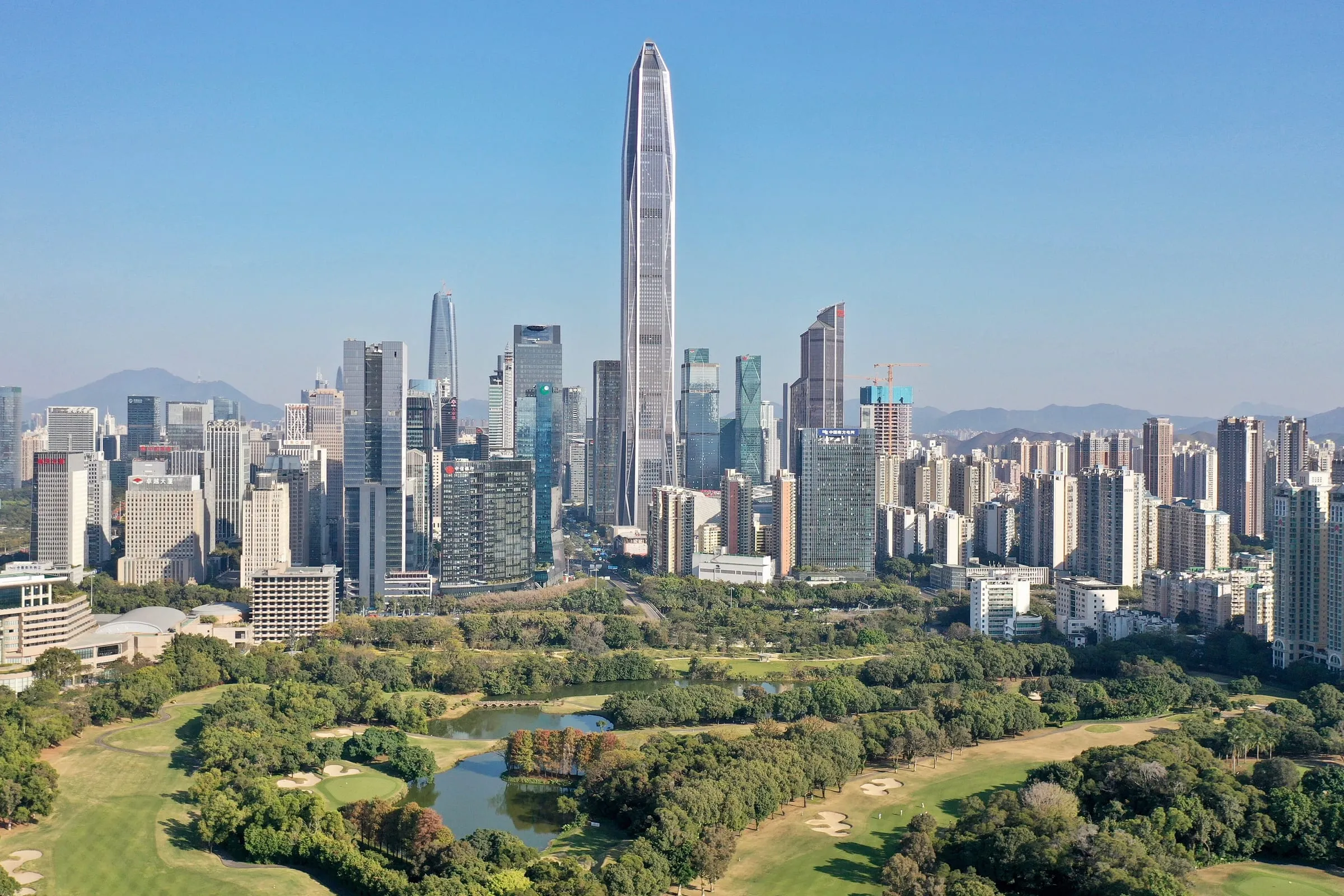 The Futian skyline in Shenzhen, seen over a park of trees and water on a clear day
